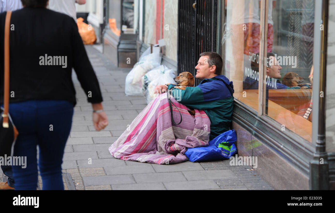 L'uomo sonno agitato per le strade di Brighton con il suo cane la sera come la gente a piedi passato Foto Stock