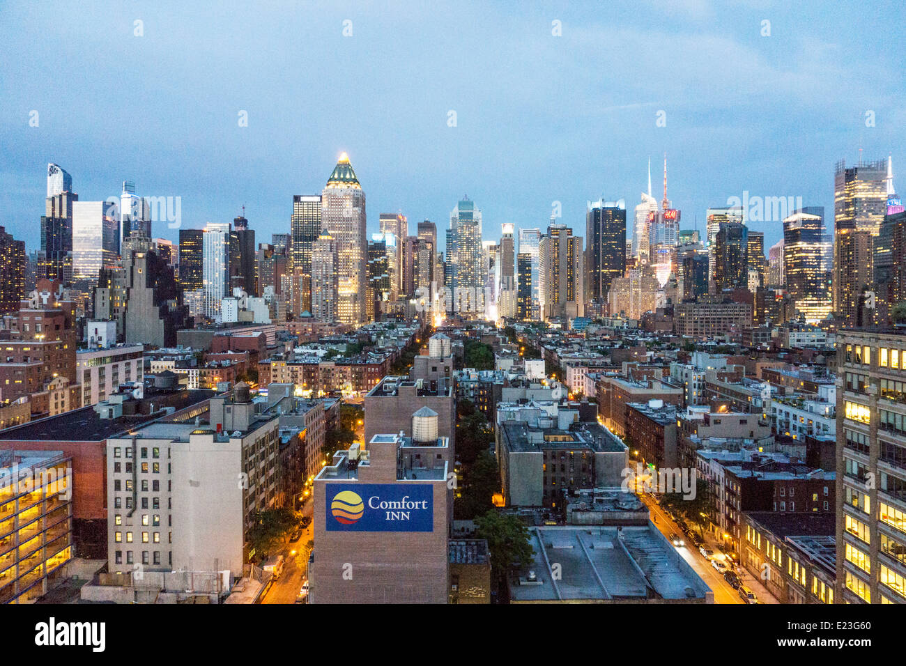 Scintillante skyline di Manhattan al crepuscolo si vede attraverso bassa tetti tetto Hells Kitchen miriade di legno serbatoi acqua street grid NYC Foto Stock