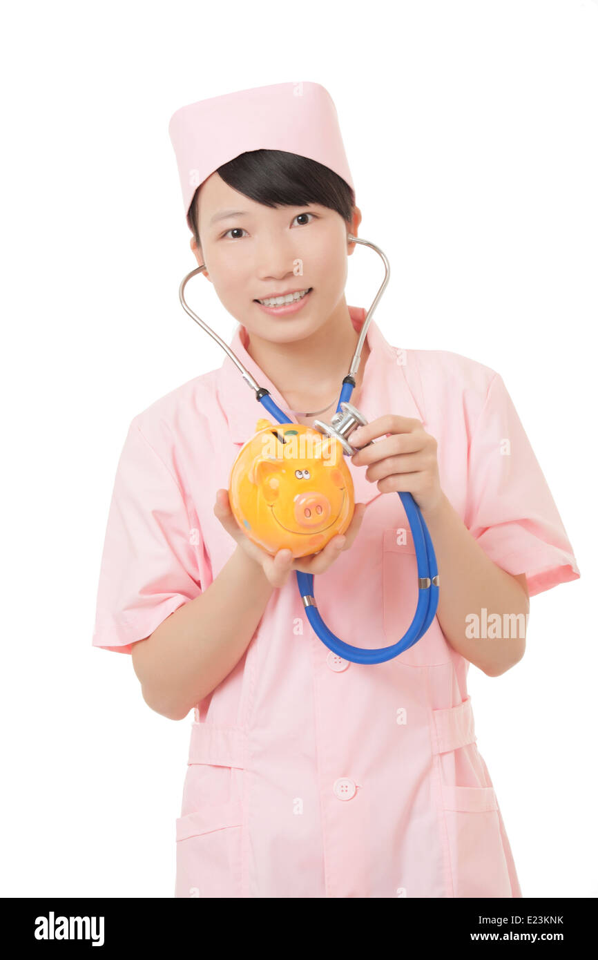 Belle infermiere cinese fingendo di ascoltare il battito cardiaco di un salvadanaio isolato su uno sfondo bianco Foto Stock
