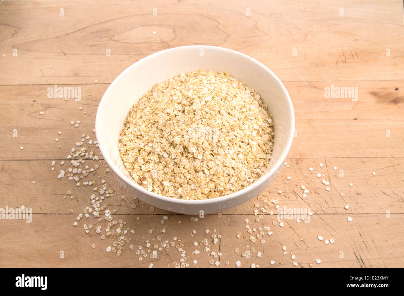 La quinoa fiocchi in un bianco terrina su una tavola di legno(11 di 18) Foto Stock