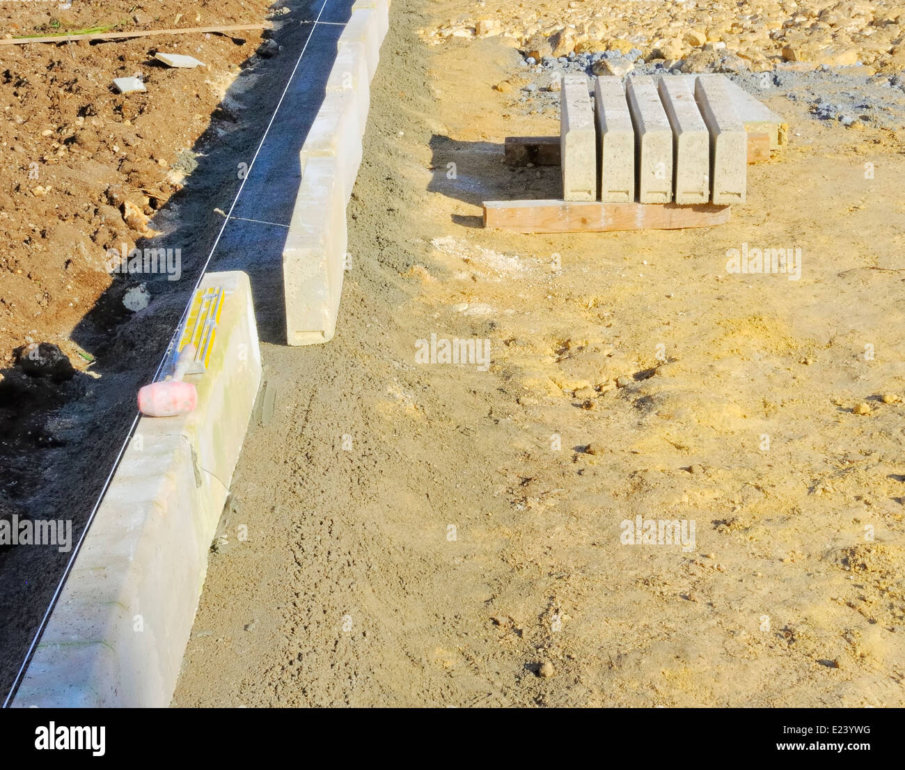 Con un martello di plastica e la livella sulla installate recentemente cordolo, che è perfettamente orizzontale ed allineata con la direzione cavo. Foto Stock