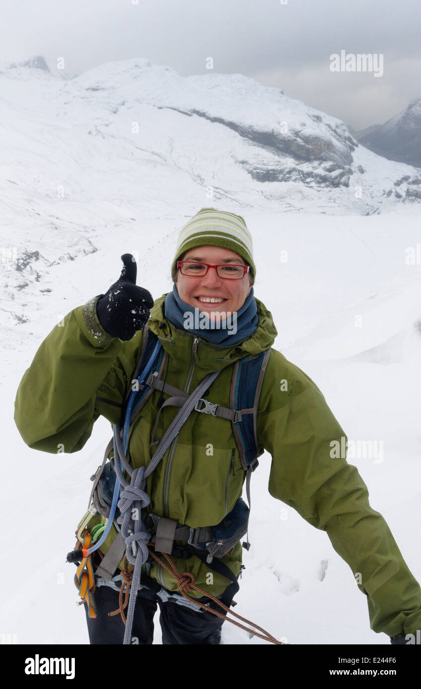 Una signora alpinista dando un allegro pollice in alto segno di alta nelle Alpi Svizzere Foto Stock
