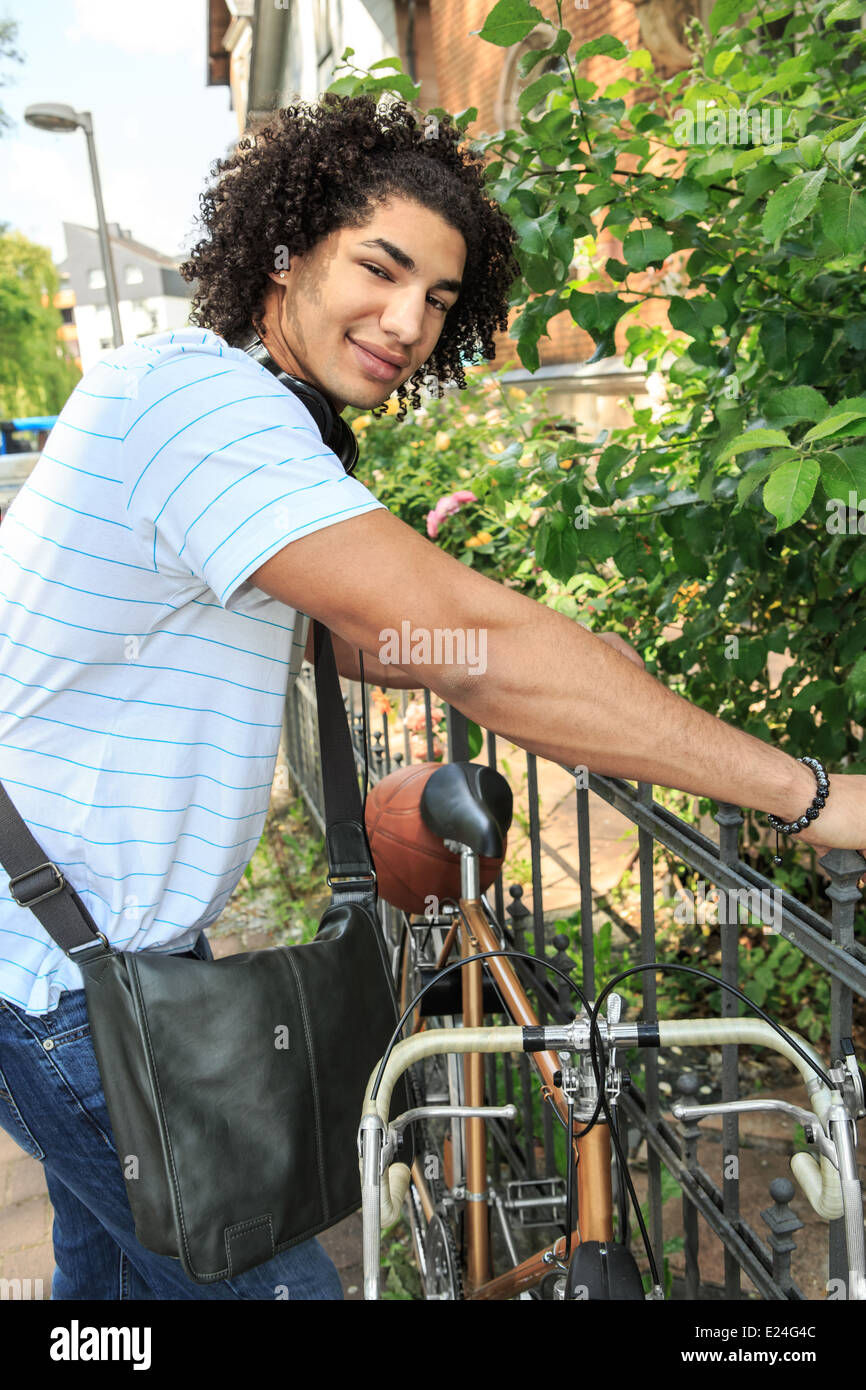 Ritratto di giovane studente maschio con una bicicletta in città Foto Stock