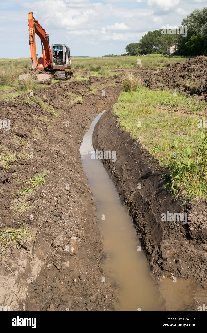 Utilizzo di un escavatore escavatore habitat per lavori di restauro su Deepdale Marsh, Burnham Deepdale, North Norfolk. Foto Stock