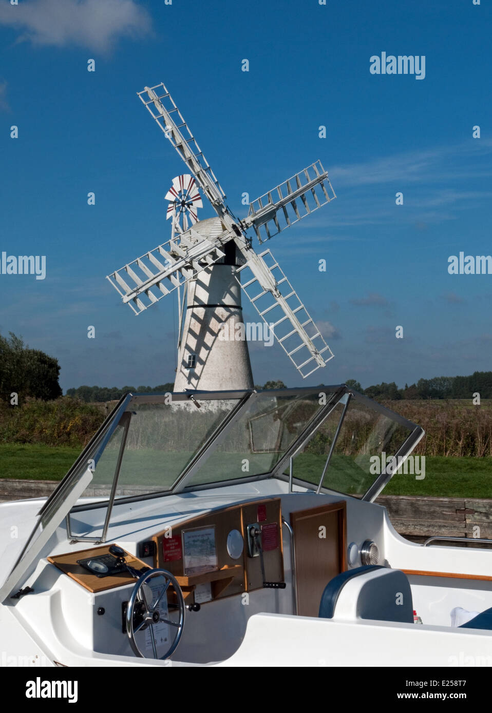 La crociera barca ormeggiata su Thurne Dyke, con mulino di drenaggio al di là, Thurne, Norfolk, Inghilterra Foto Stock