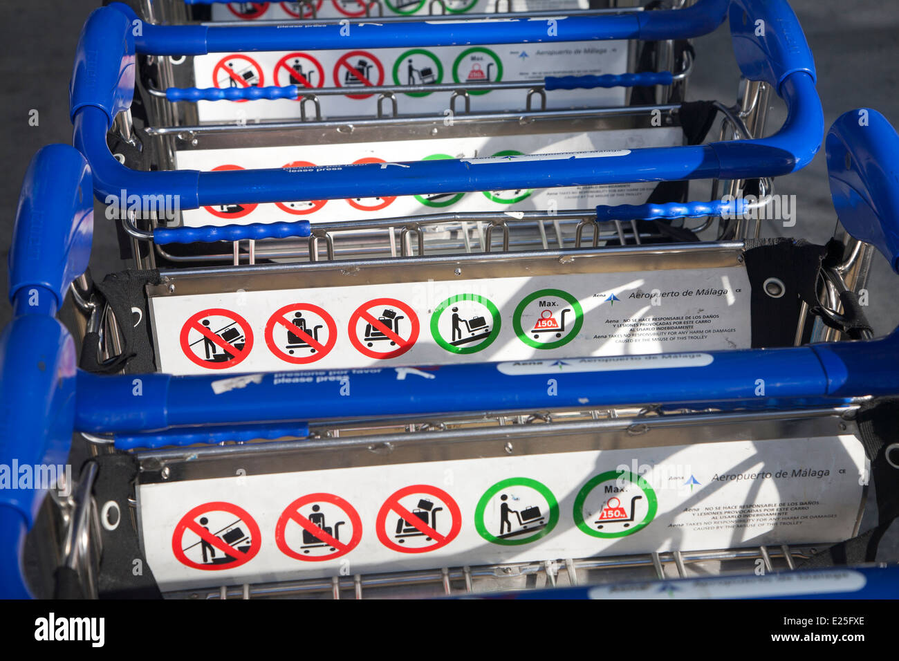 Close up della linea di una pila di carrelli portabagagli con informazioni sulle regole di utilizzo, dall'aeroporto di Malaga, Spagna Foto Stock