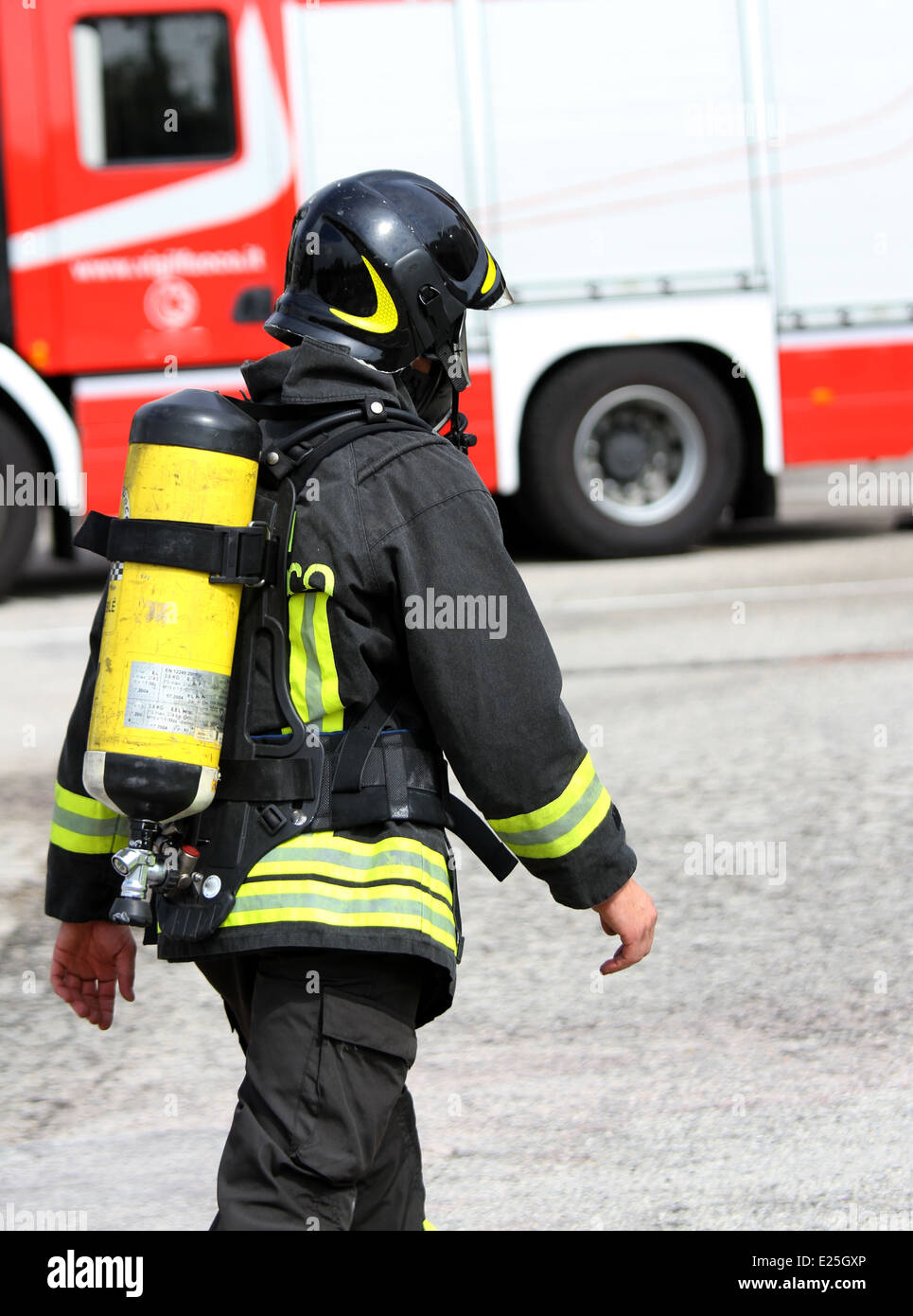 Vigile del fuoco italiano con la bombola di ossigeno e il casco cammina verso il fuoco Foto Stock