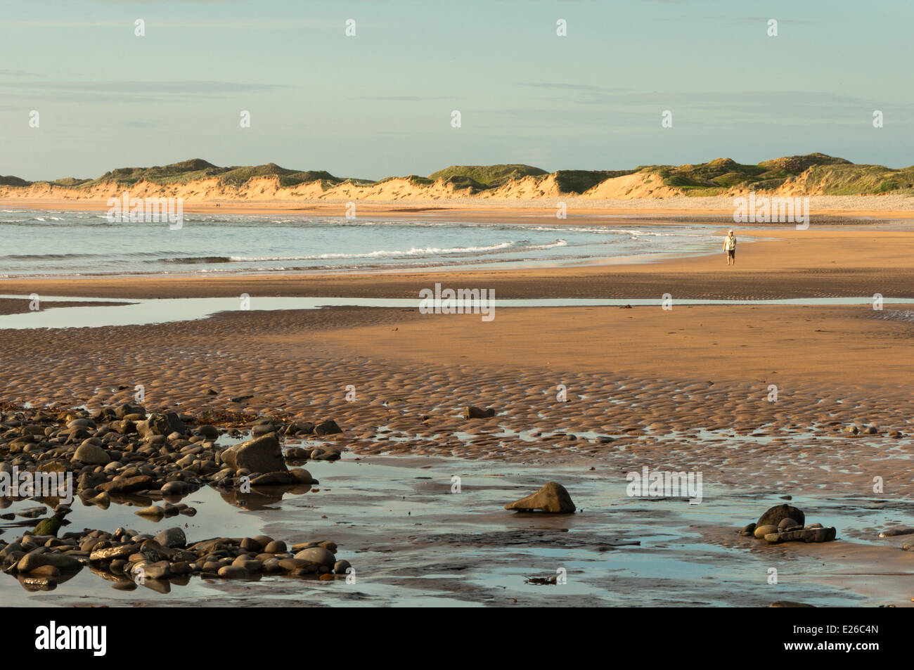 Walker sulla spiaggia sulla costa occidentale dell' Irlanda in serata luce estiva Foto Stock