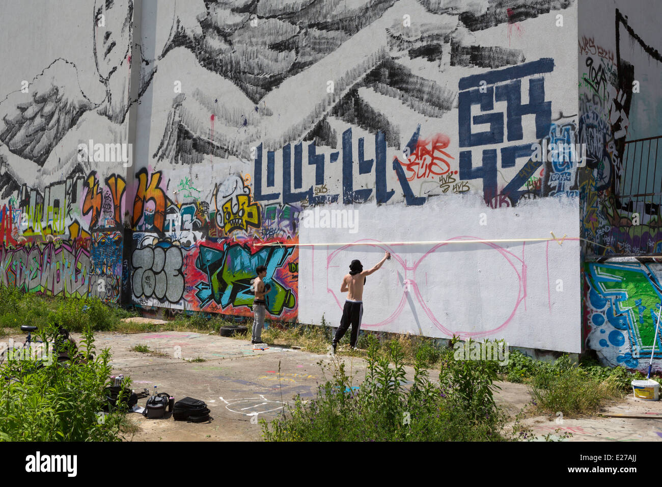 Giovani squatter la spruzzatura di graffiti su un muro a Friedrichshain, una parte di Berlino, Germania Foto Stock
