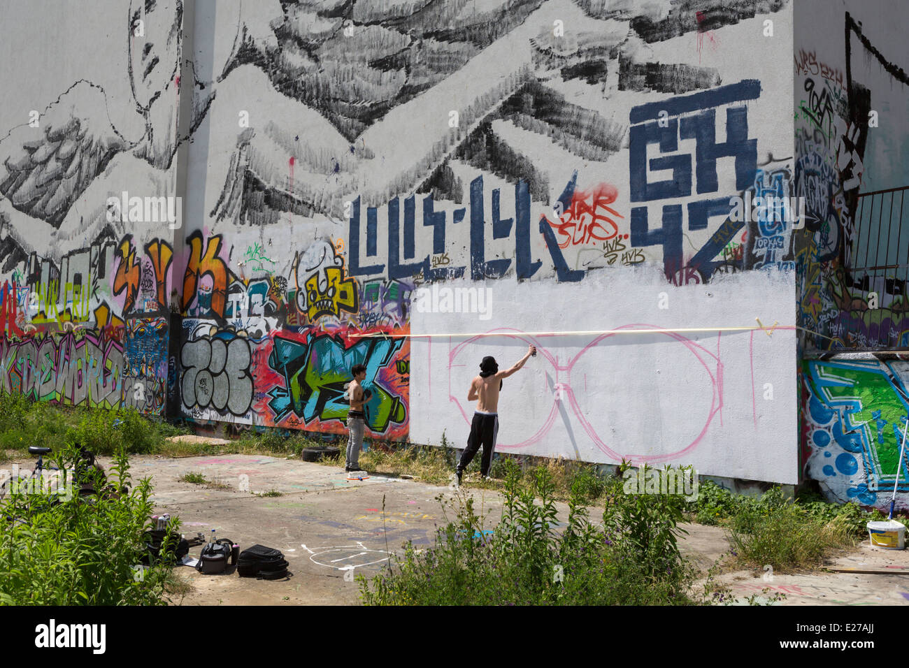 Giovani squatter la spruzzatura di graffiti su un muro a Friedrichshain, una parte di Berlino, Germania Foto Stock