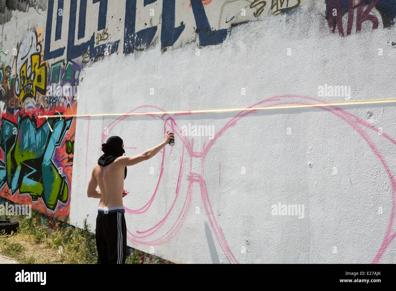 I giovani la spruzzatura di graffiti su un muro a Friedrichshain, una parte di Berlino, Germania Foto Stock