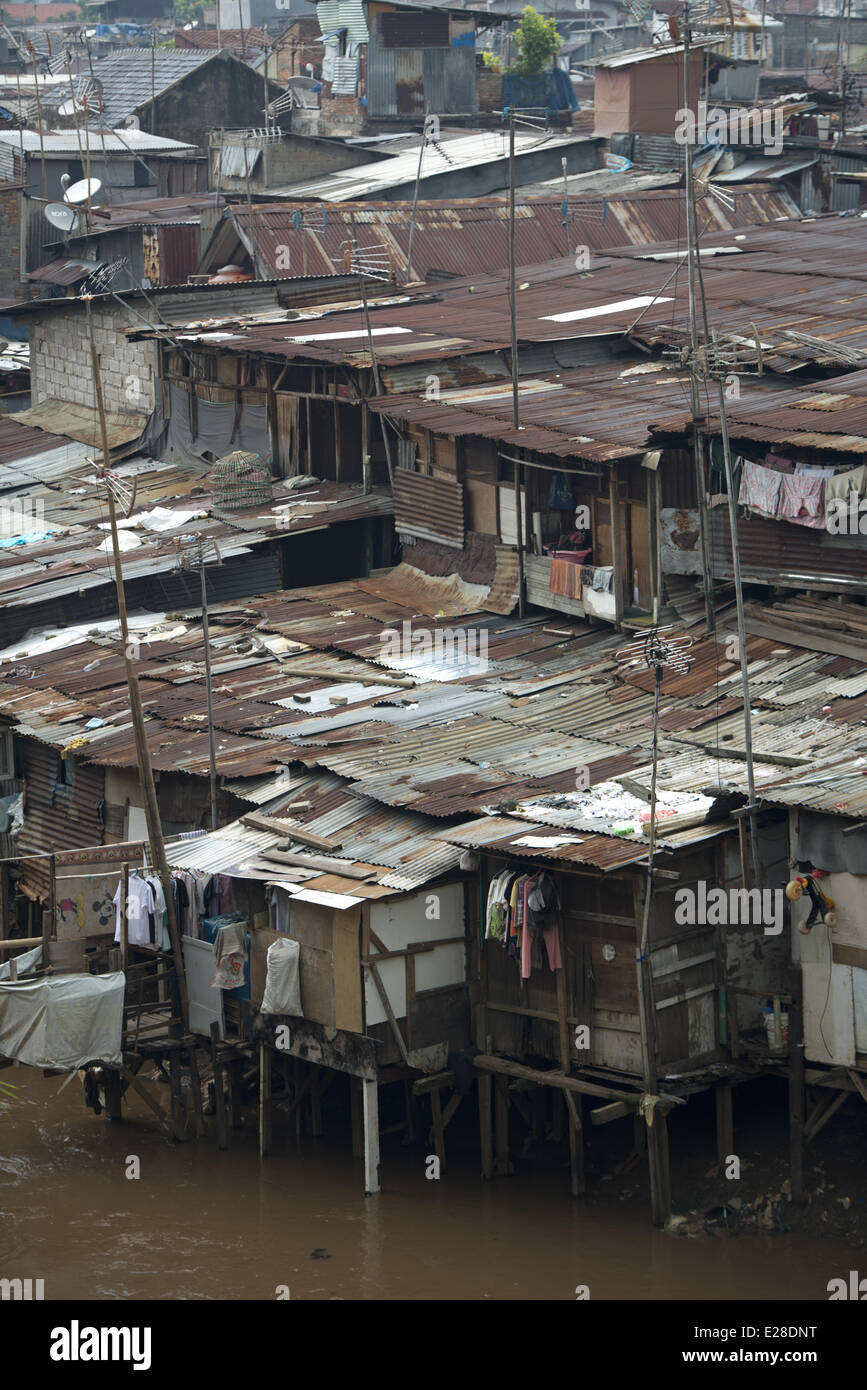 Stilted baracche con tetti in lamiera accanto al fiume in città, quartiere Manggarai, Giacarta, Java, Indonesia, Dicembre Foto Stock
