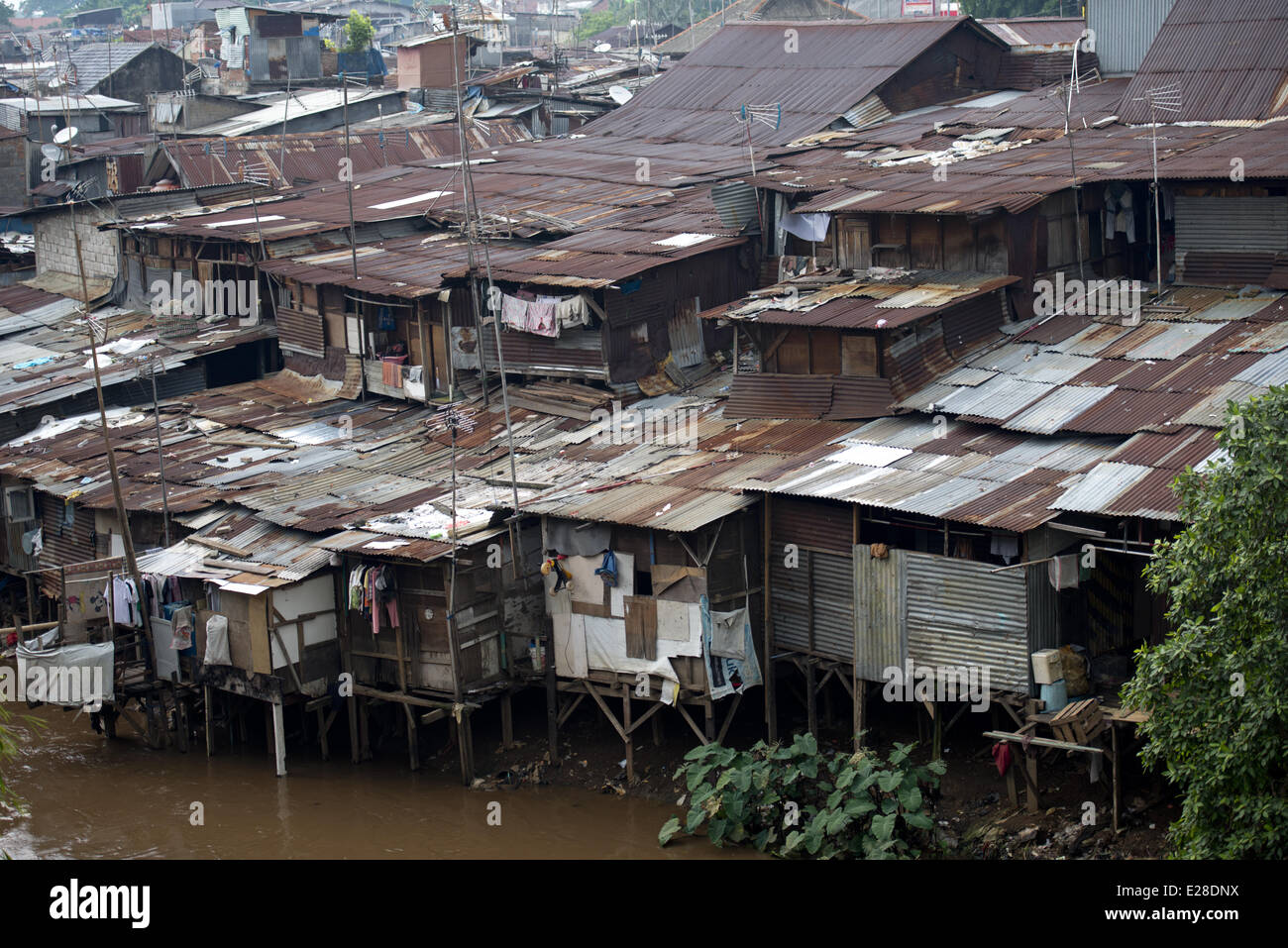 Stilted baracche con tetti in lamiera accanto al fiume in città, quartiere Manggarai, Giacarta, Java, Indonesia, Dicembre Foto Stock