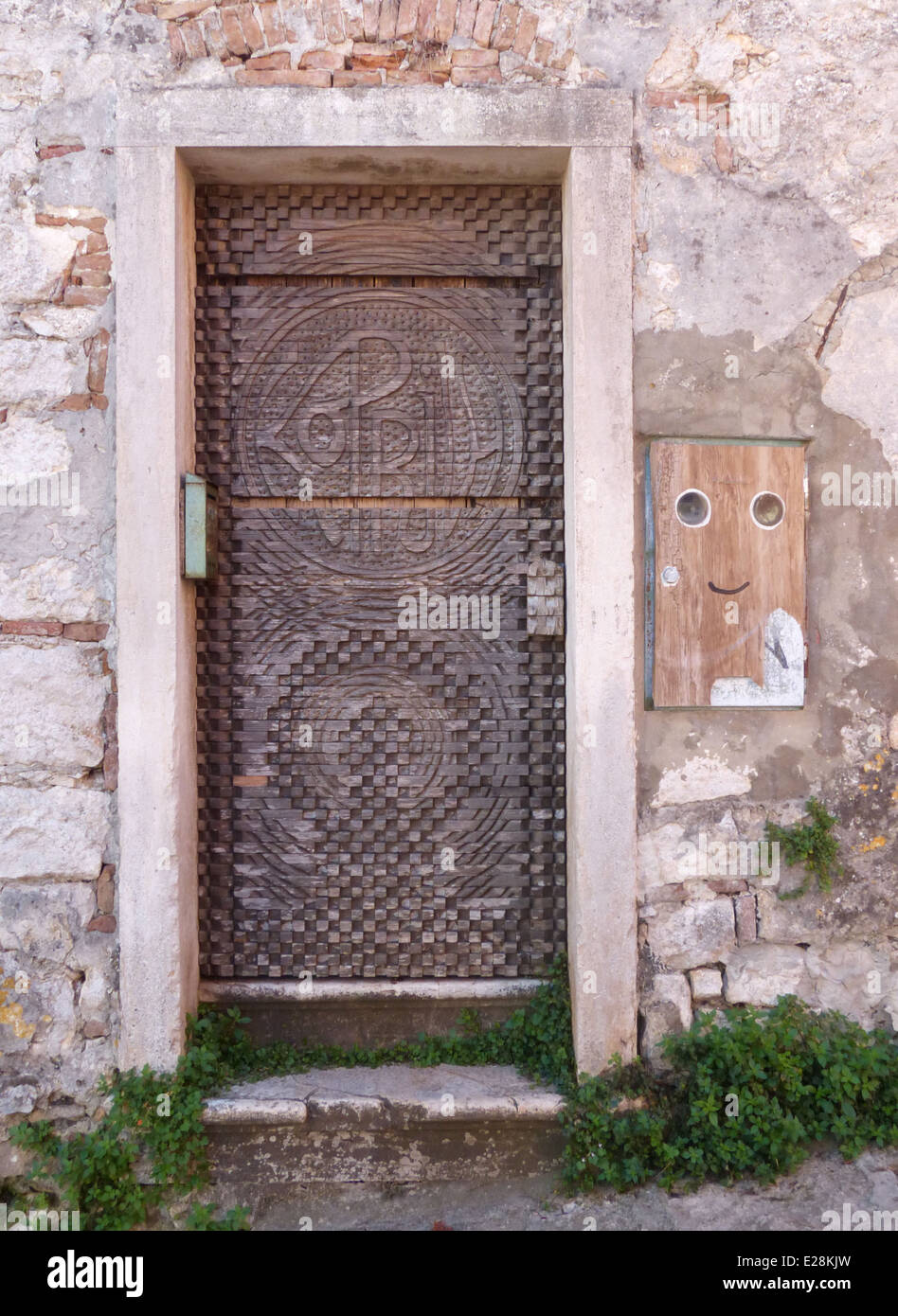 Una vecchia porta di legno con una scatola sulla parete accanto ad esso con una faccina sorridente sul Foto Stock