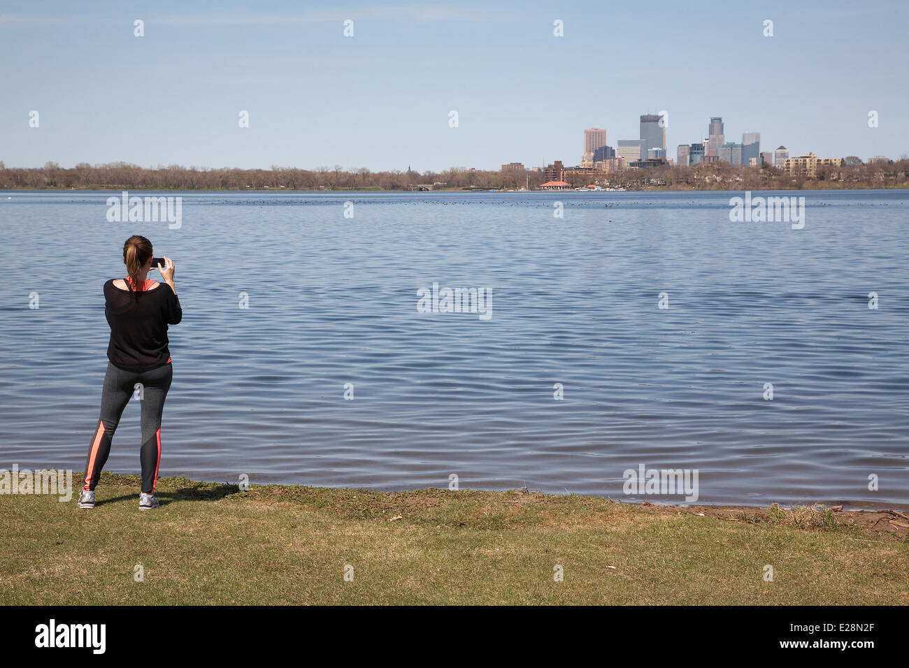 Una giovane ragazza di scattare una foto della città di Minneapolis sul lago Calhoun, Minnesota, Stati Uniti d'America Foto Stock