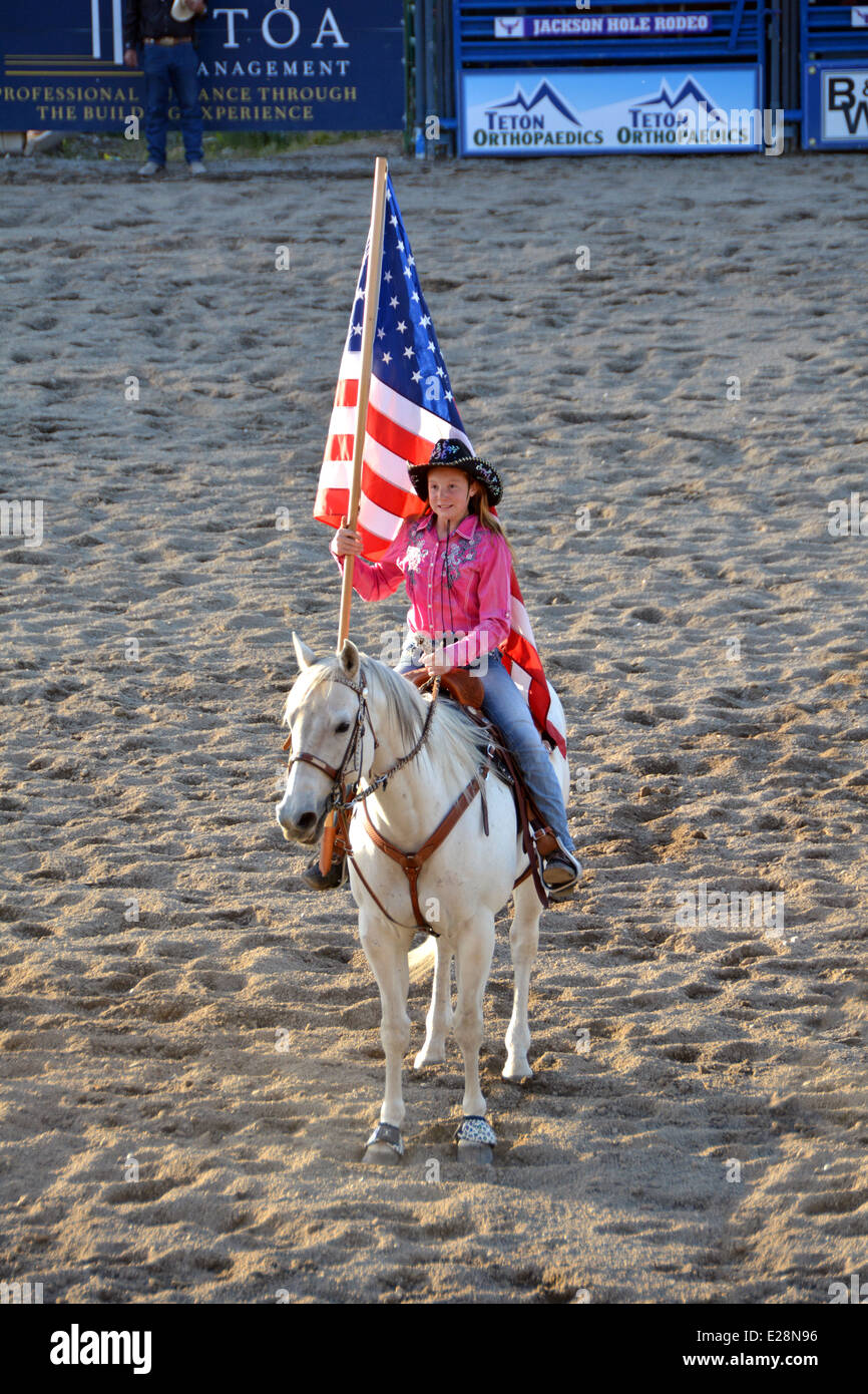 11 anno vecchia ragazza su un cavallo portante la bandiera in apertura di Jackson Hole rodeo. Foto Stock