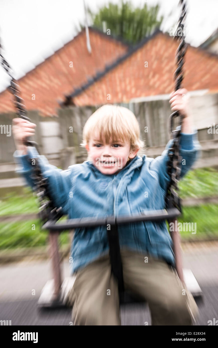 Giovane ragazzo biondo sorrisi sulle altalene Foto Stock