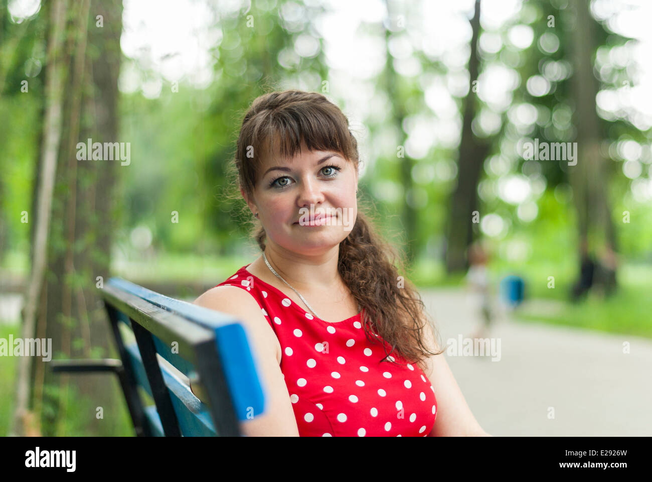 Ritratto di una bellissima ragazza su una panchina nel parco. Foto Stock