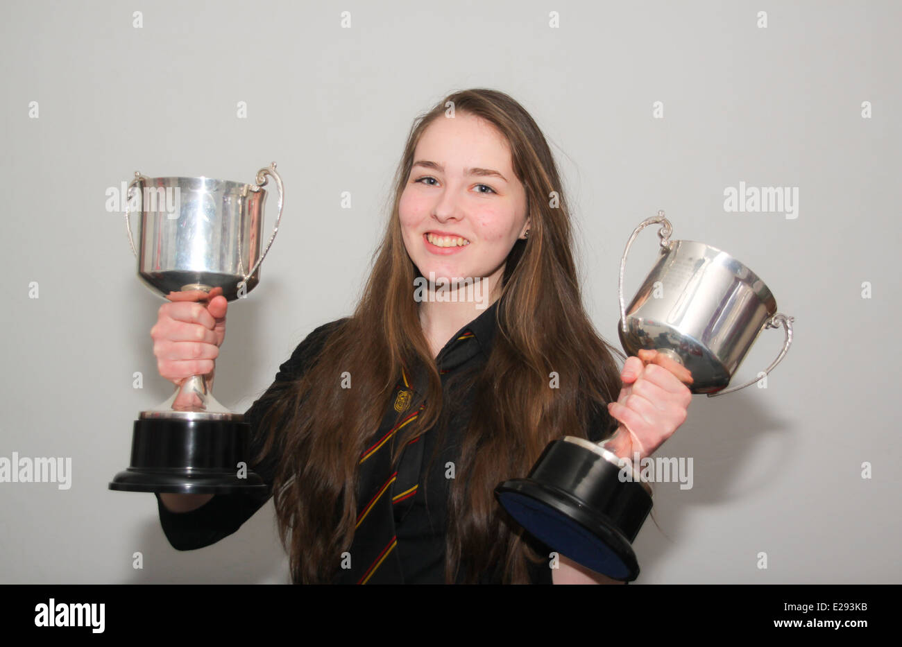 Giovane ragazza adolescente azienda coppe d'argento di trofei di scuola Foto Stock