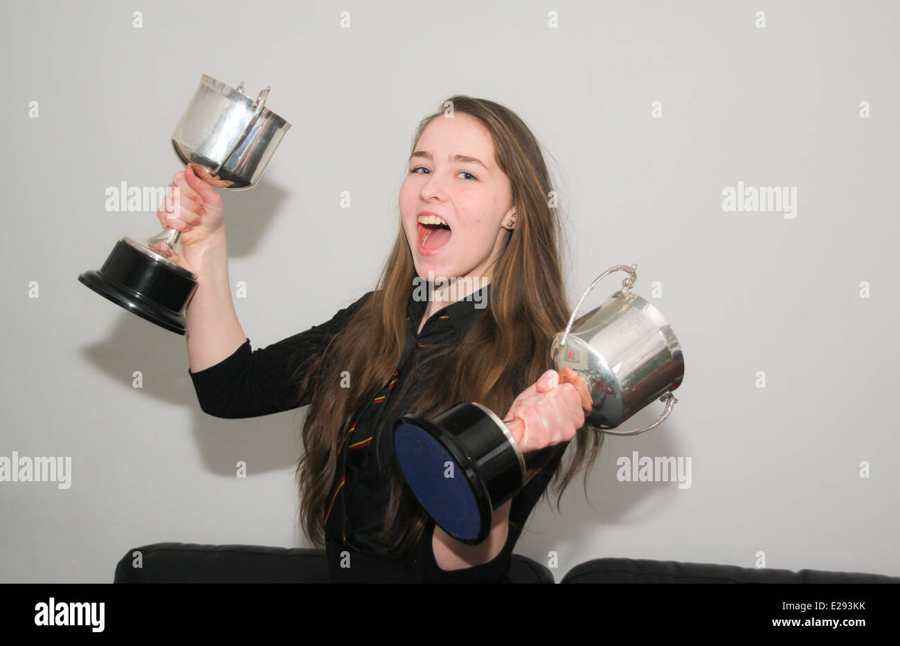 Giovane ragazza adolescente azienda coppe d'argento di trofei di scuola Foto Stock