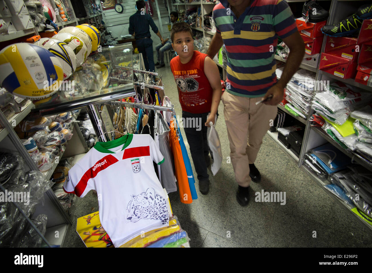 Tehran, Iran. 16 Giugno, 2014. Un ragazzo iraniano passeggiate passato l'Iran la nazionale di calcio abito a una usura sport shop nel centro di Teheran. Credito: Morteza Nikoubazl/ZUMA Press/Alamy Live News Foto Stock