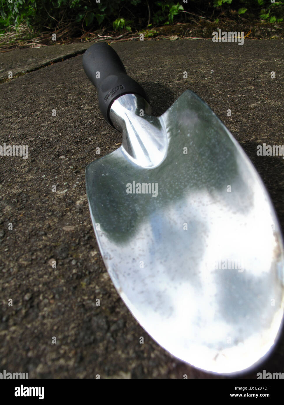 Acciaio inossidabile giardino frattazzo su lastra di calcestruzzo Foto Stock