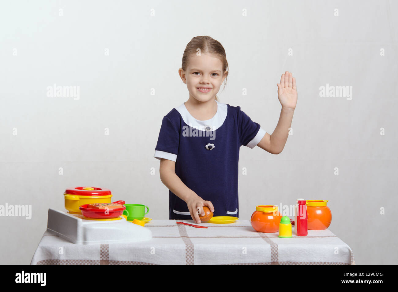Bambina di cinque anni giocando in bambini mistress piatti a un tavolo coperto con un panno Foto Stock