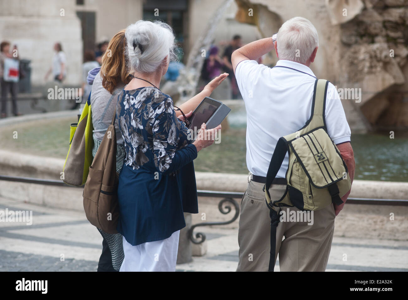 Roma Italia - Anziani turisti da una fontana di Piazza Navona con tavoletta digitale Foto Stock