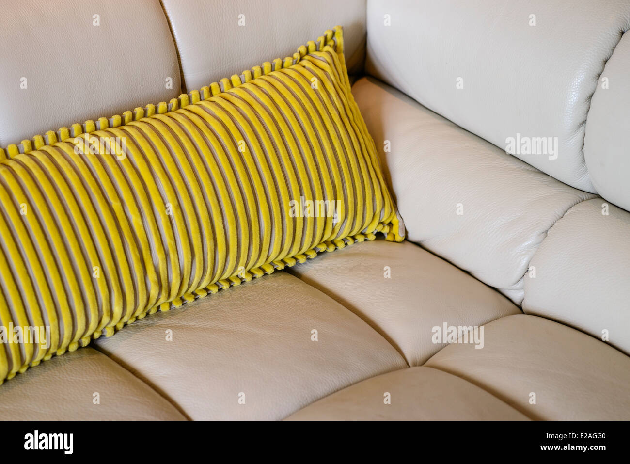 Cuscino giallo su un beige divano in pelle Foto Stock