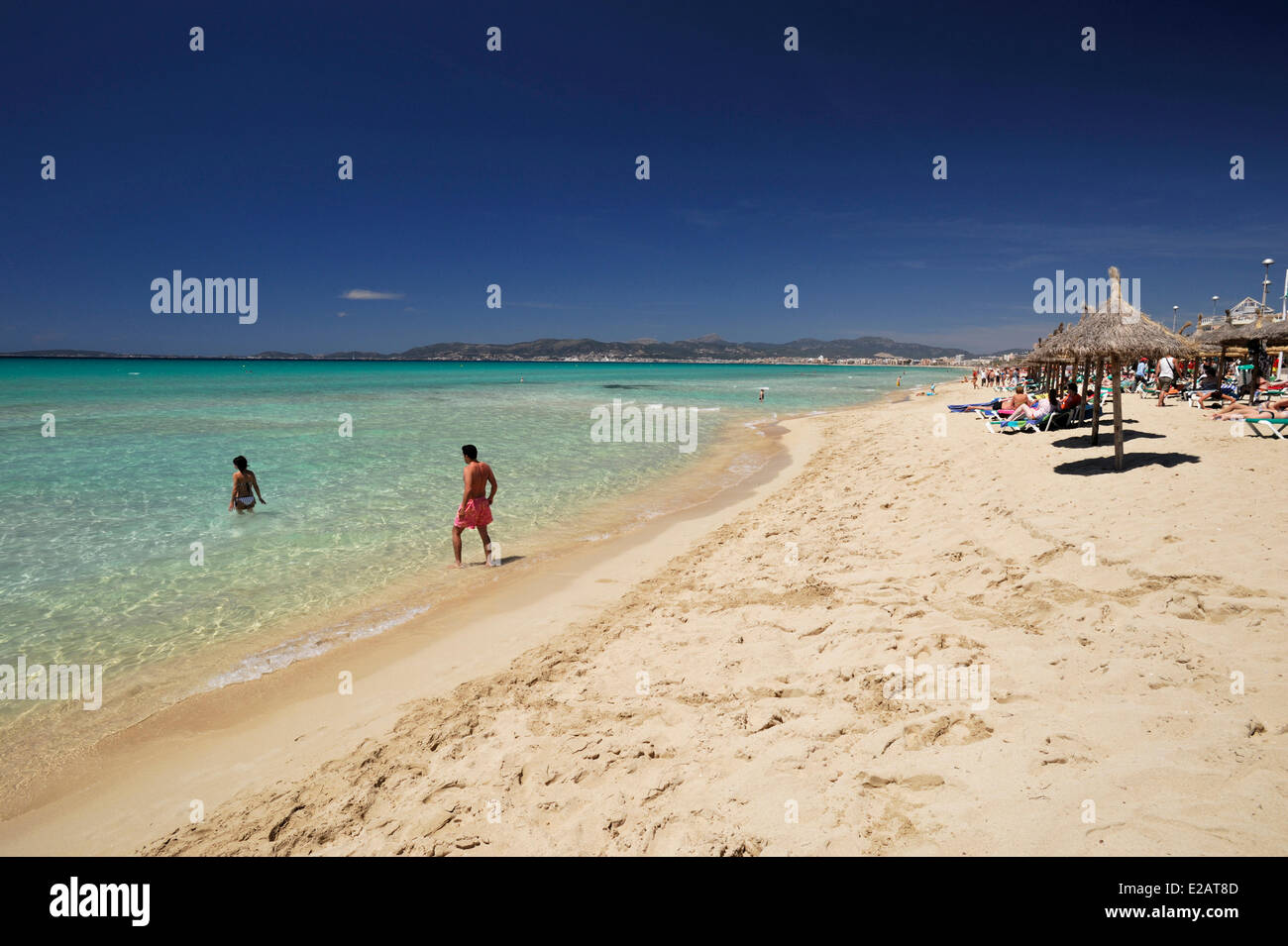Isole Baleari Spagna, Mallorca, S'Arenal, El Arenal, spiaggia Palma, vacanzieri in acqua nella parte anteriore di ombrelloni di paglia Foto Stock