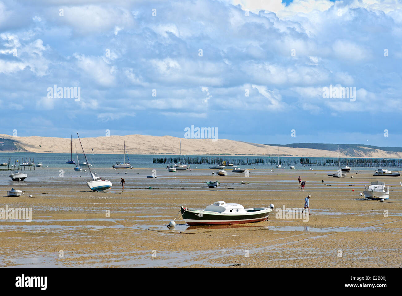 Francia, Gironde, Baia di Arcachon, Cap Ferret, gli uomini camminare sulla sabbia a bassa marea con barche nel mezzo delle Dune du Pyla in Foto Stock