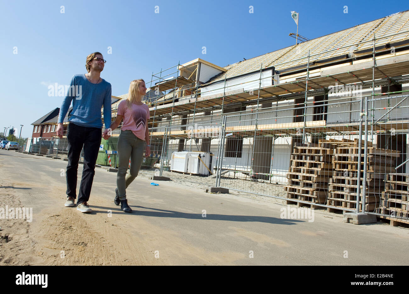 Coppia giovane è a piedi attraverso la strada dove la loro nuova casa è in fase di costruzione Foto Stock