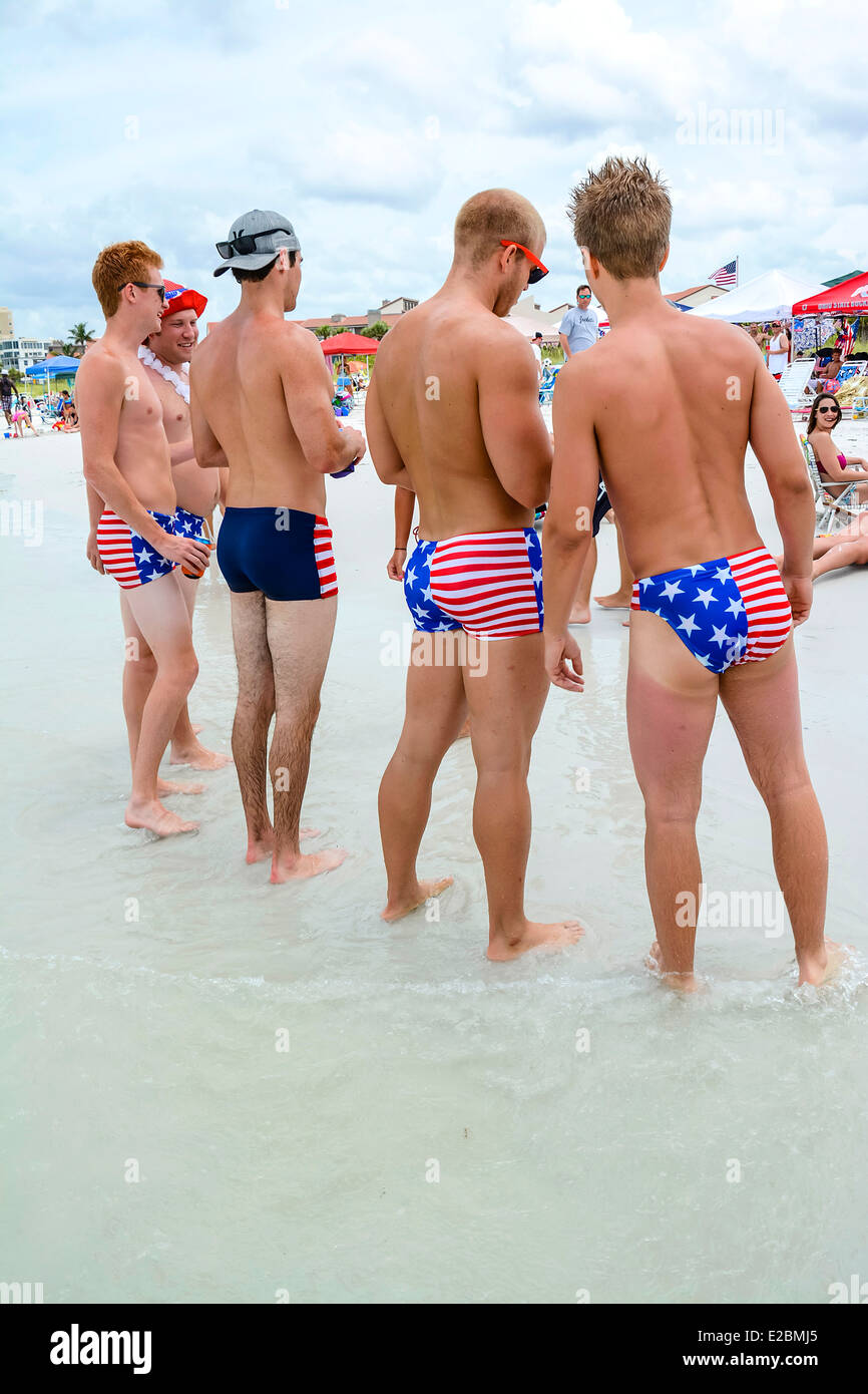 Un gruppo di collegio patriottico-di età compresa tra gli uomini a stelle e strisce abiti nuotare puntone la loro roba sulla spiaggia il 4 luglio Foto Stock