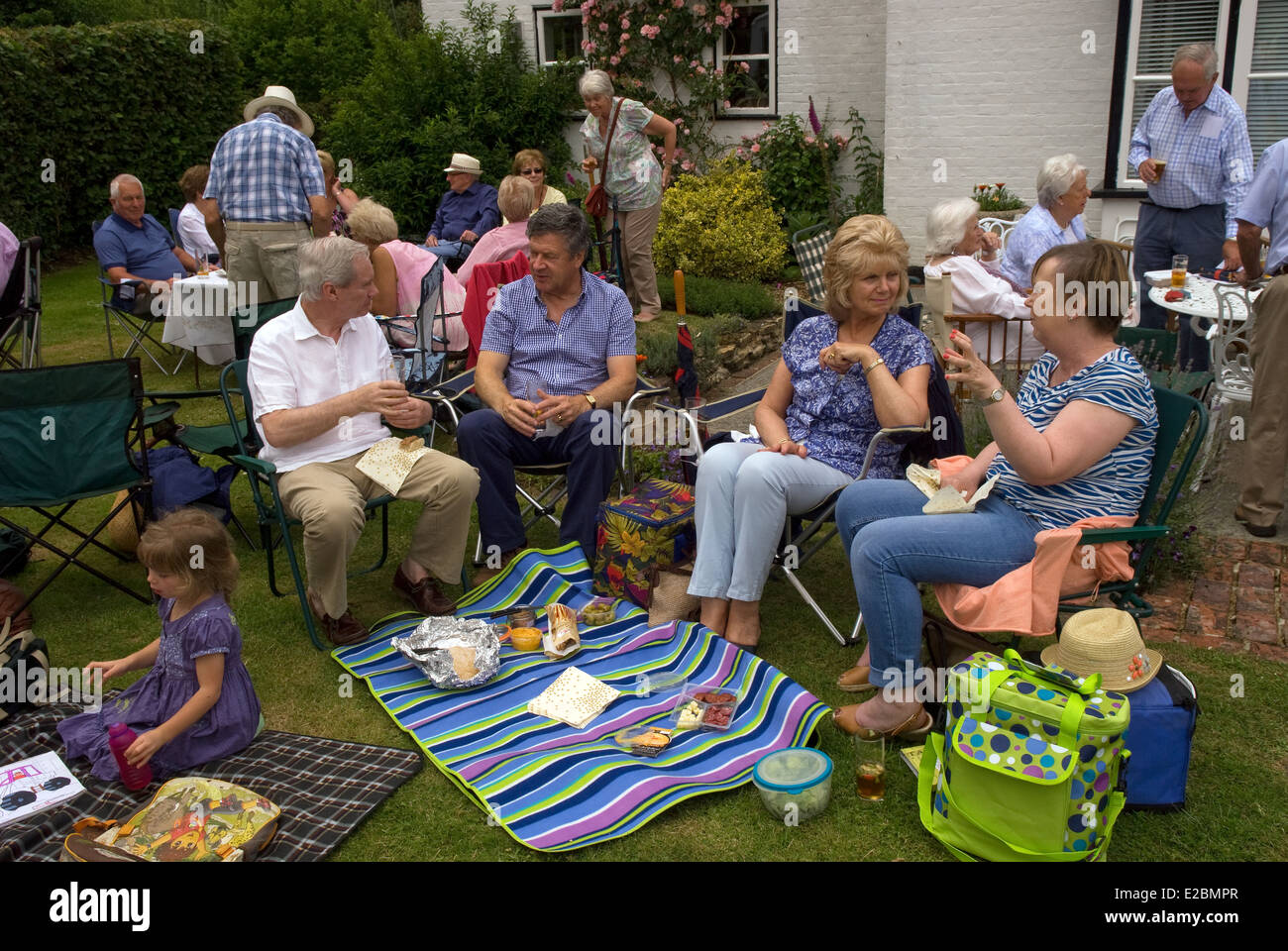 Il gruppo di coloro che godono di un picnic e bevande a summer party in giardino, Standford, Hampshire, Regno Unito. Foto Stock