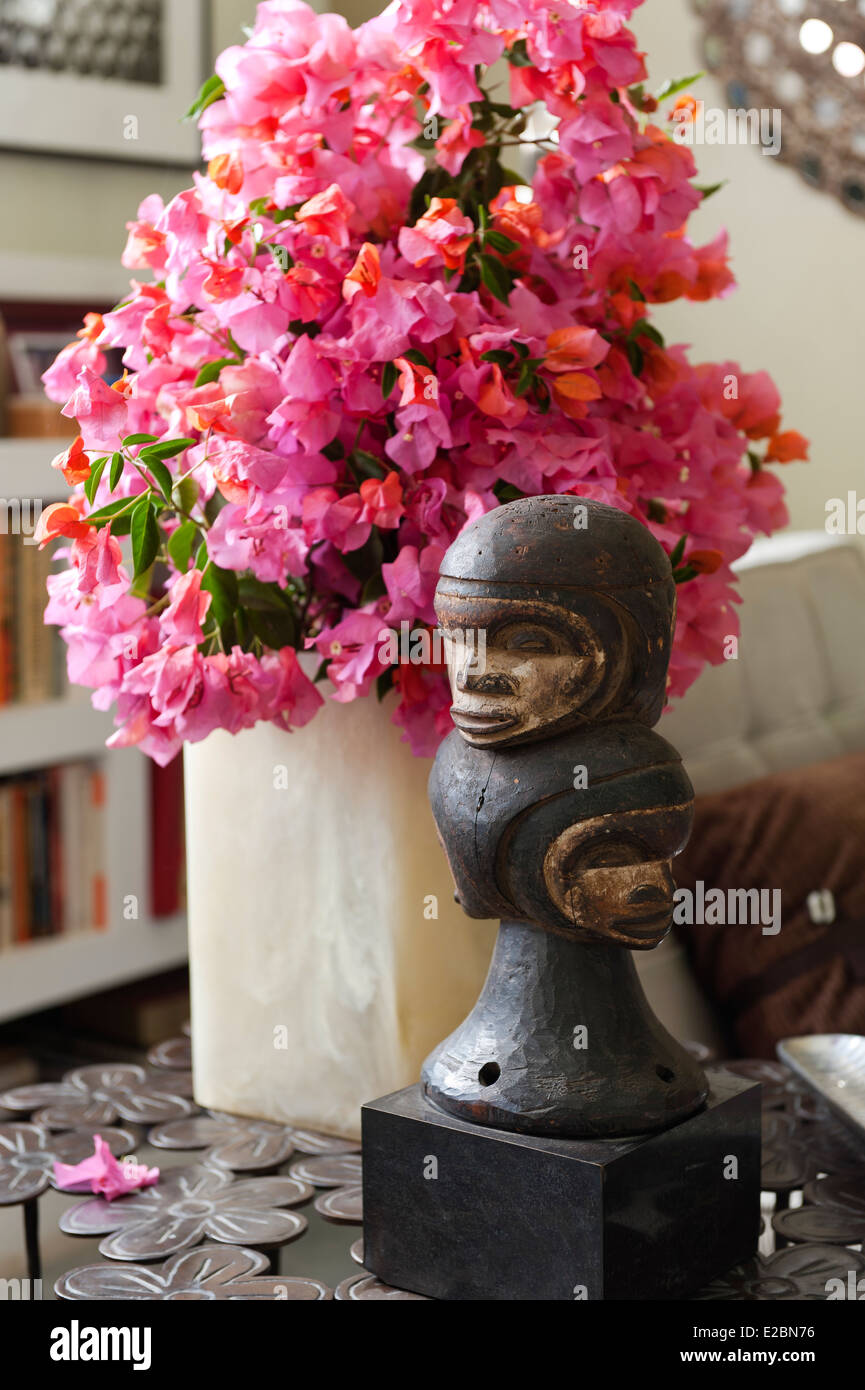 Fiori di colore rosa e la scultura scolpita sul lato tavolo in Baja home Foto Stock