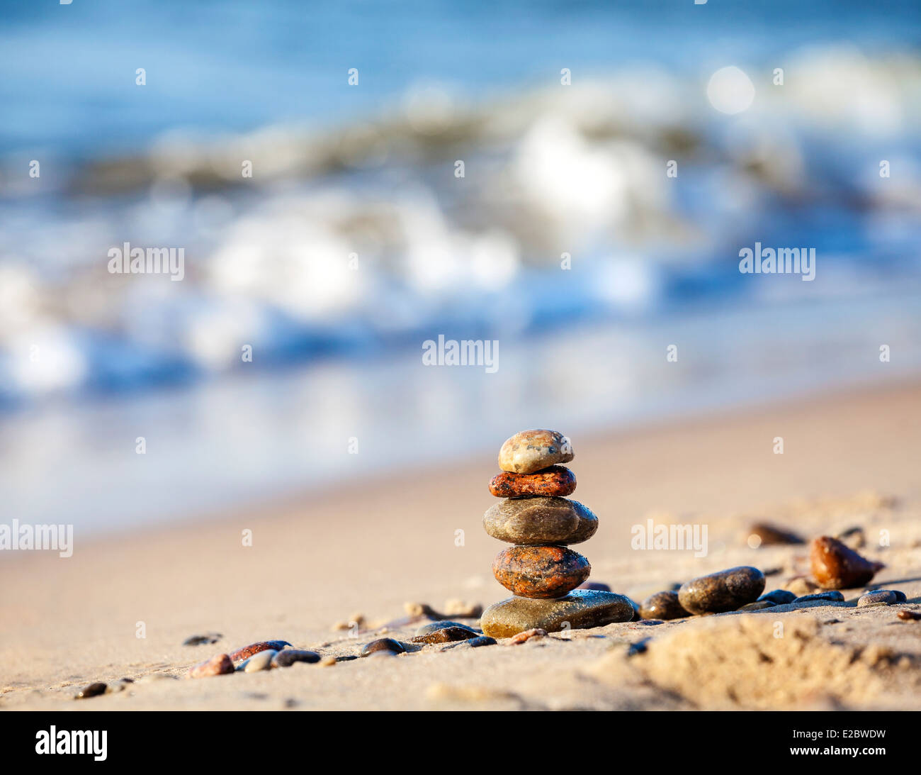 Piramide di pietre sulla sabbia che simboleggiano zen, armonia, equilibrio, blu oceano sullo sfondo . Foto Stock