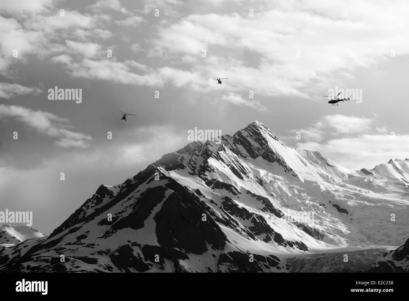 Tre elicotteri oltre le montagne scoscese vette con un ghiacciaio in Alaska sudorientale. Foto Stock