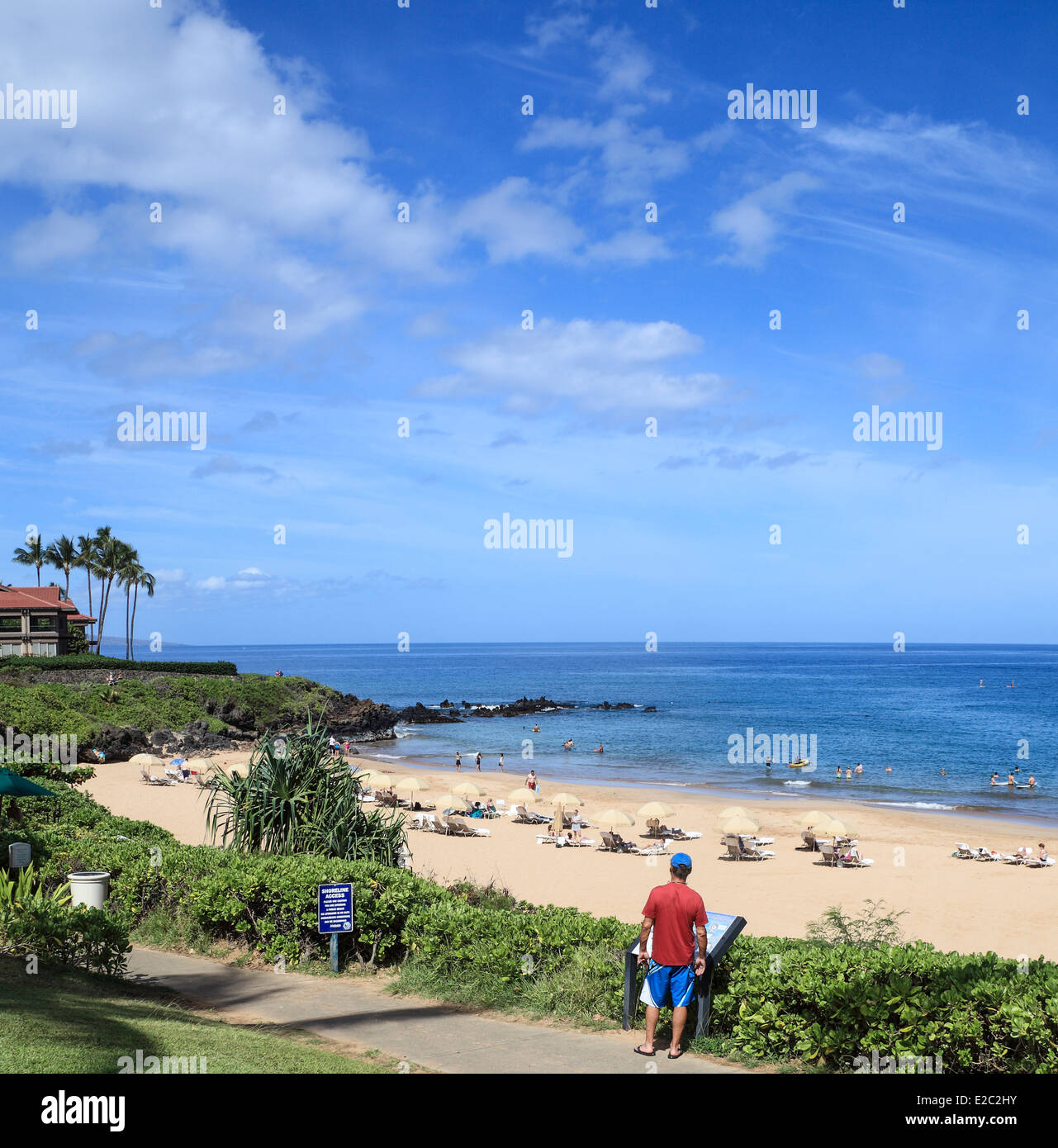 Uomo legge segno lungo la passeggiata costiera nella parte anteriore del Wailea Beach a Maui Foto Stock