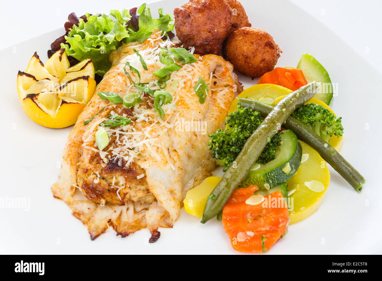 Pesce grigliato servito con un medley di brani di ortaggi e frittelle di farina di mais. Foto Stock