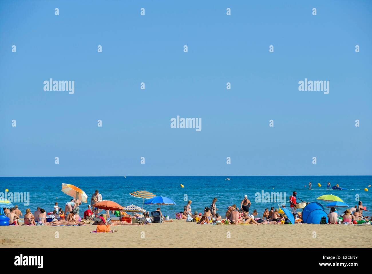 Francia, Herault, Valras Plage, vacanzieri in medio di ombrelloni prendendo sole su di una spiaggia di sabbia con mare in background Foto Stock