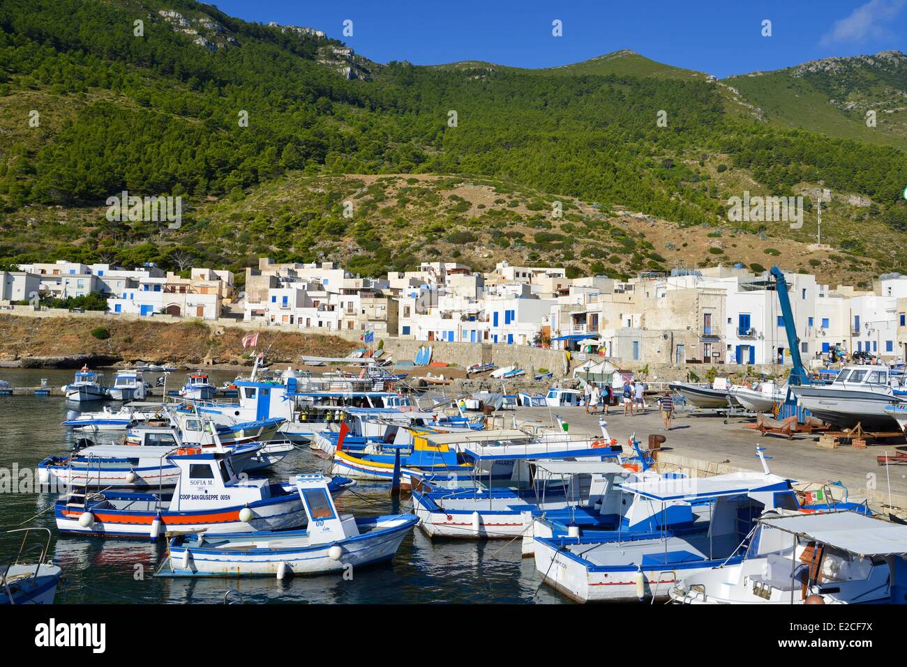 L'Italia, sicilia, isole Egadi, isola di Marettimo, colorate barche da pesca in porto con case di città piazze e pareti dipinte di bianco in background Foto Stock