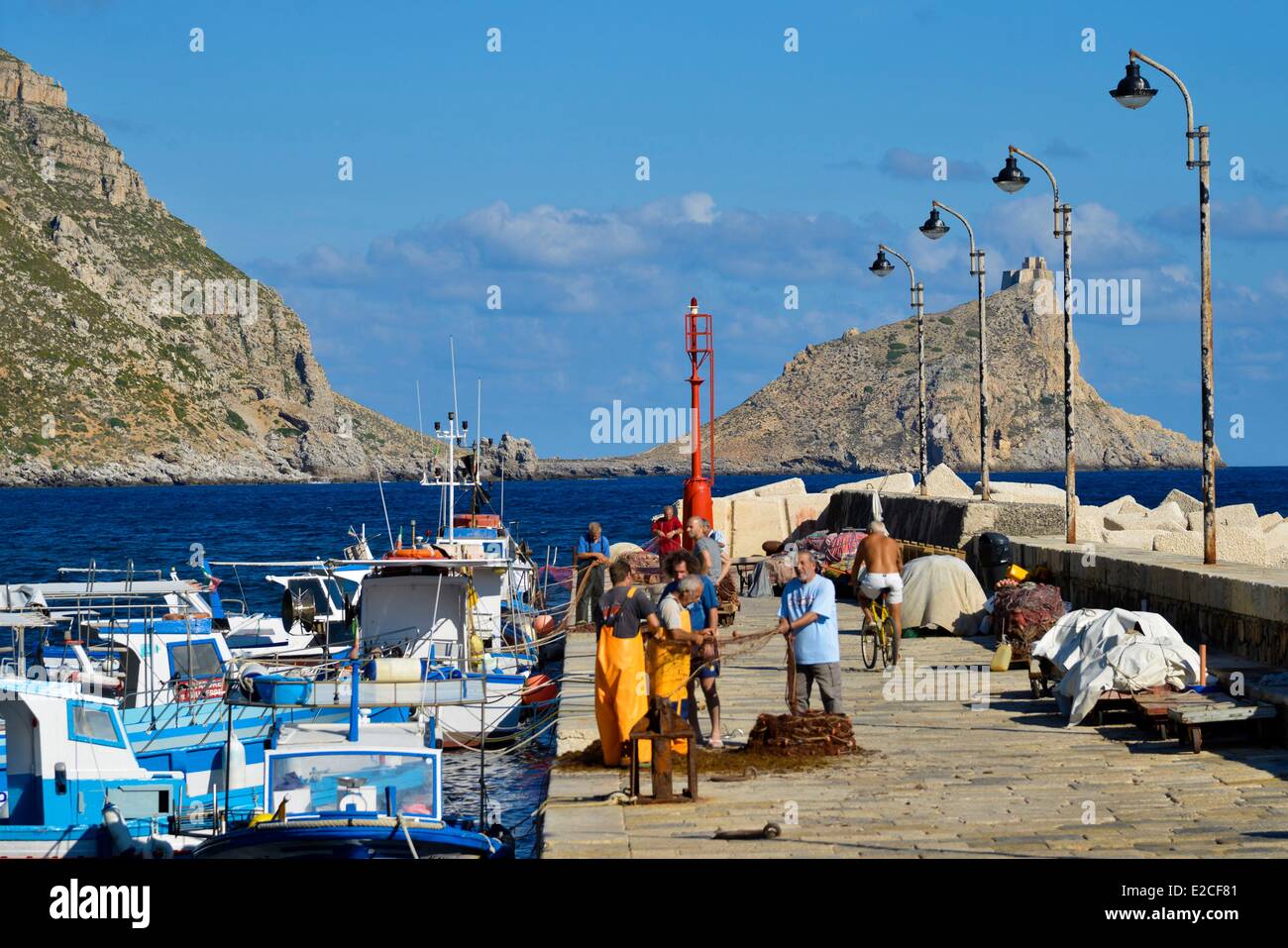 L'Italia, sicilia, isole Egadi, isola di Marettimo, porto di pesca, pesca su un molo con Troia Pointe in background Foto Stock