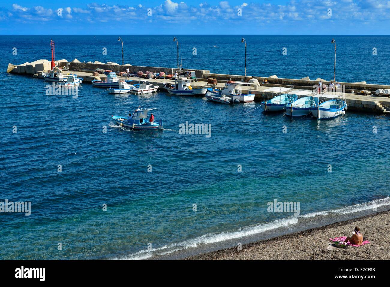 L'Italia, sicilia, isole Egadi, isola di Marettimo, porto di pesca, i pescherecci con reti da traino dock in legno con un carattere lettura su una spiaggia in primo piano Foto Stock