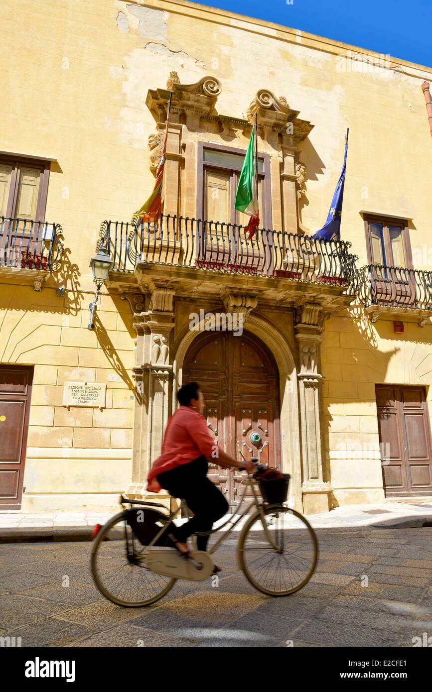 L'Italia, Sicilia, Trapani, centro storico, Fardella Fontana palace, donna su una bici passando davanti ad una porta di legno Foto Stock