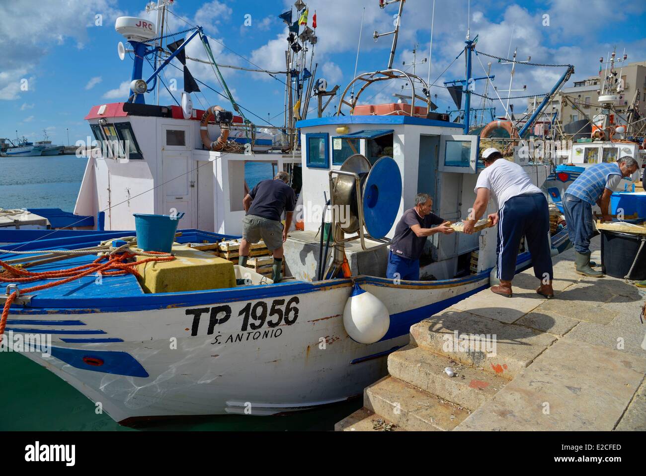 L'Italia, Sicilia, Trapani, centro storico, porto di pescatori, mens off-caricamento scatole di pesce da un peschereccio per traino Foto Stock