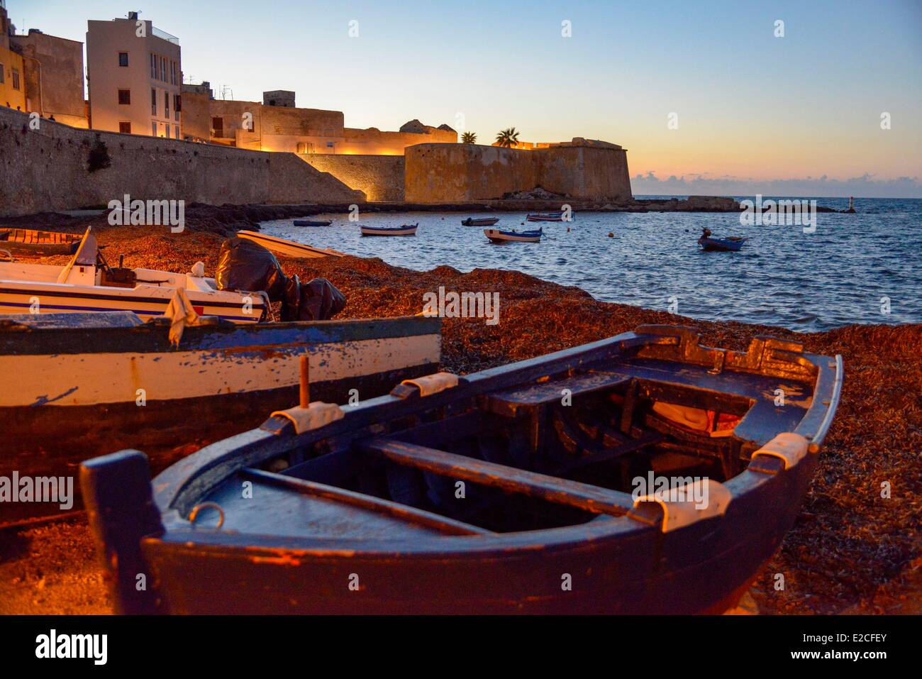 L'Italia, Sicilia, Trapani, centro storico, barche in legno sulla spiaggia porta Ossuna ai piedi della Passeggiata della Tramontana al tramonto con il Conca fortezza in background Foto Stock