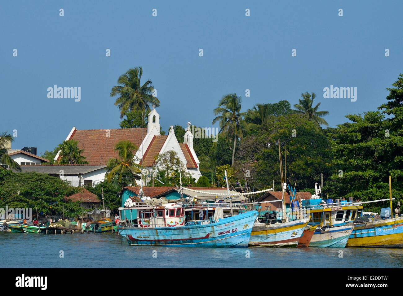 Sri Lanka Provincia Occidentale Distretto Gampaha Negombo colorati in legno per la pesca a strascico per la pesca con una chiesa di sfondo Foto Stock