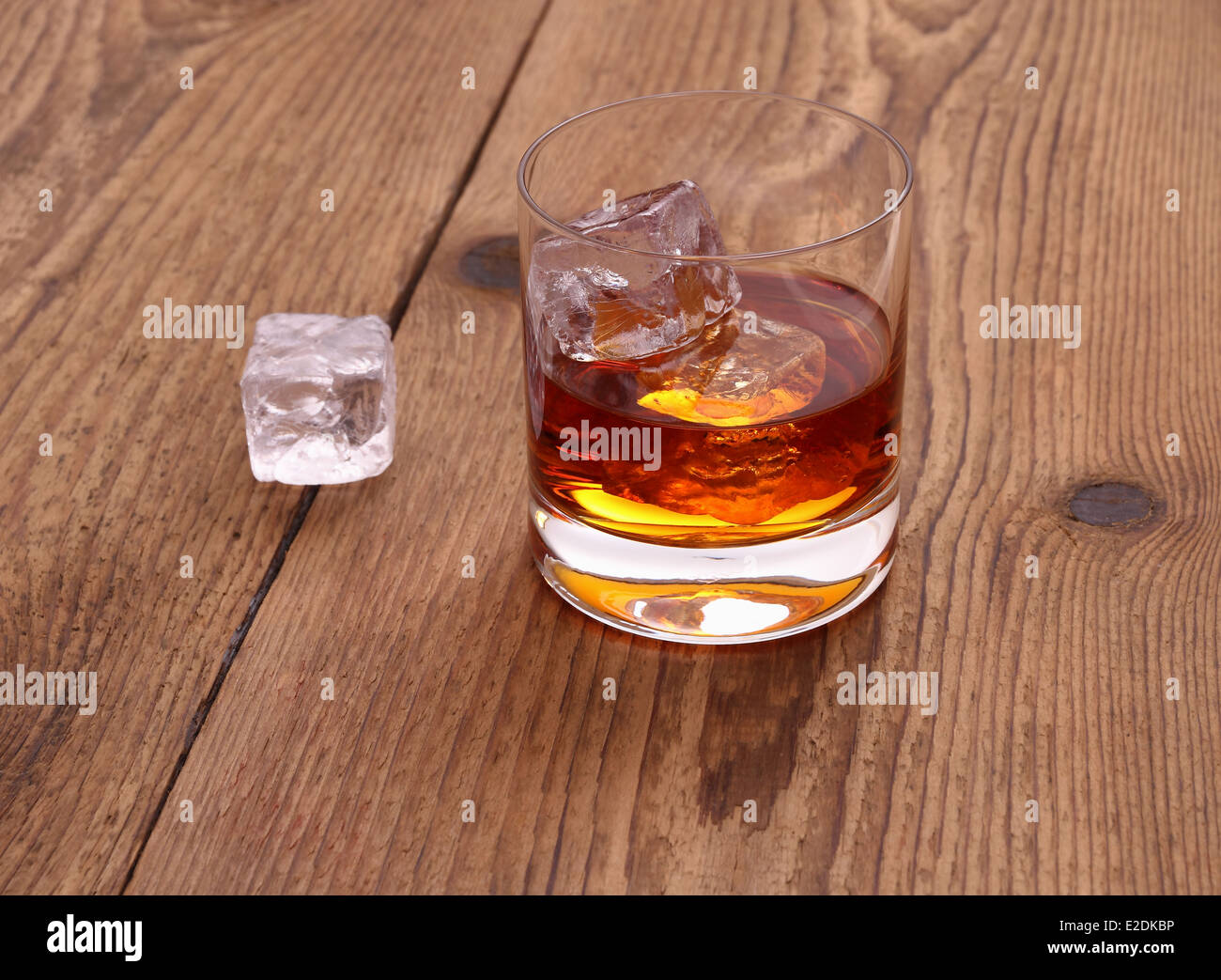 Il whiskey con cubetti di ghiaccio in vetro su uno sfondo di legno, close up Foto Stock