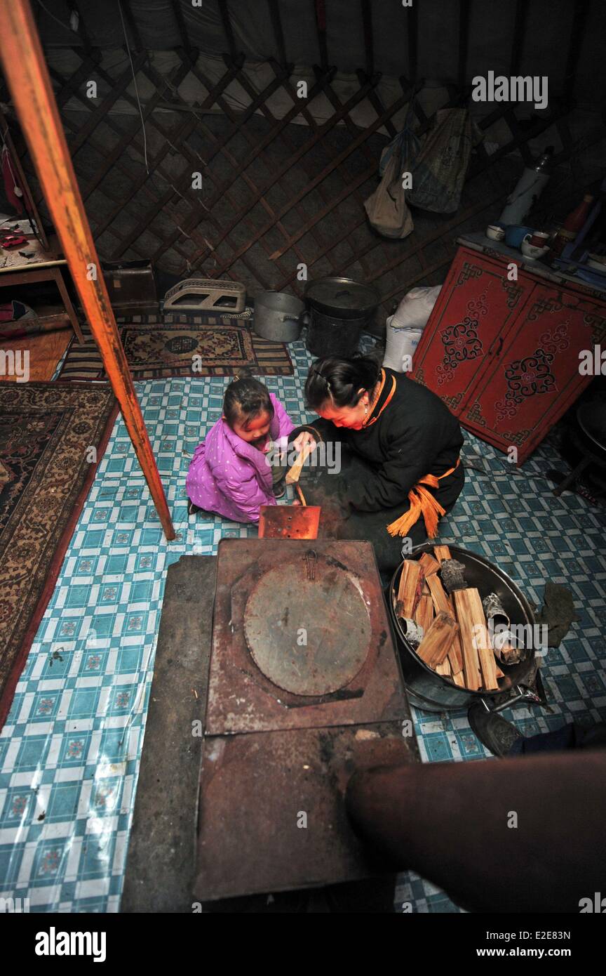 Mongolia, Tov provincia, Baganuur, padre in piedi dalla figlia, tenendo registro da camino in yurta Foto Stock