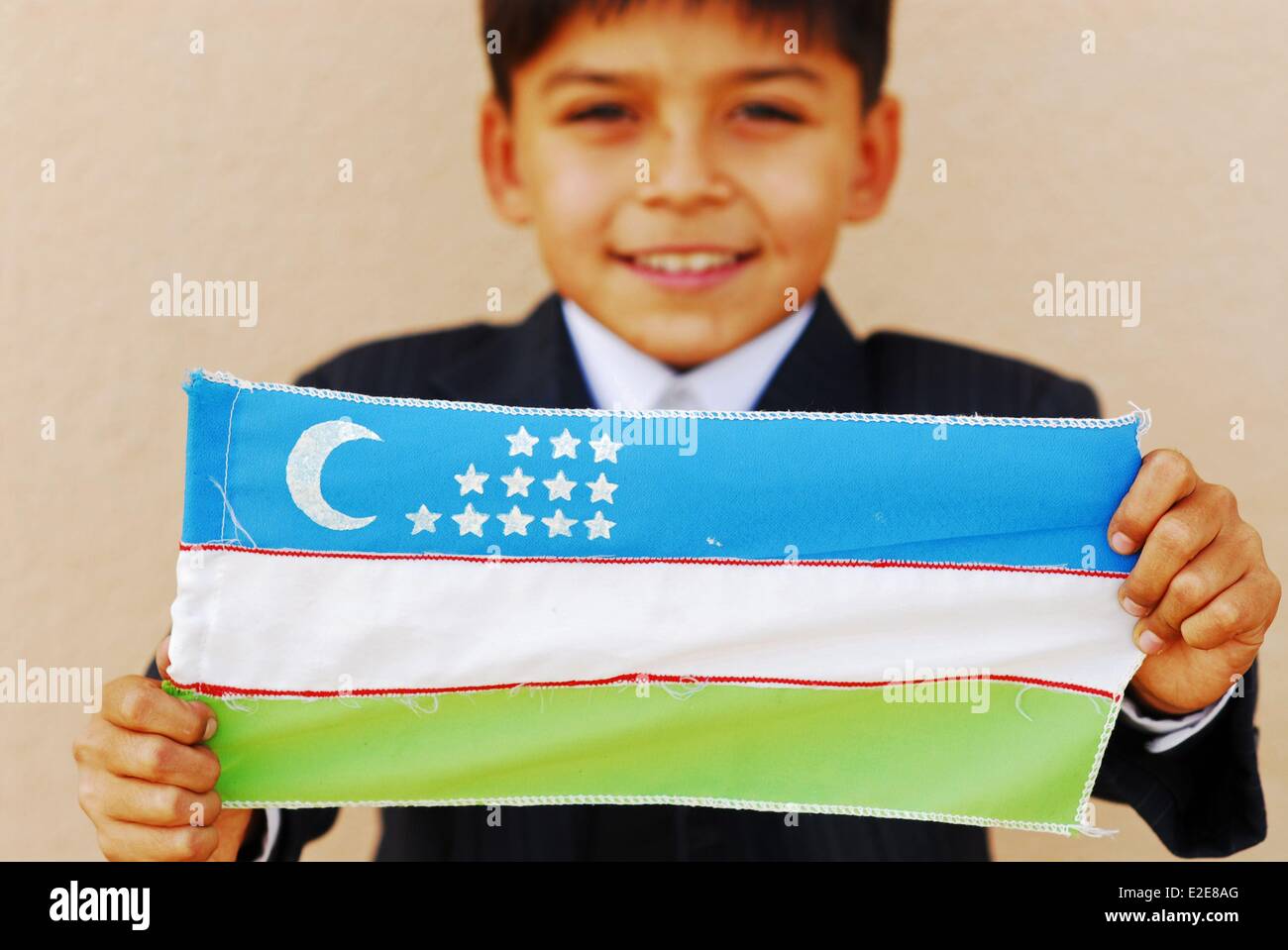 Uzbekistan, Fergana, close-up ritratto di un ragazzo sorridente bandiera di contenimento Foto Stock